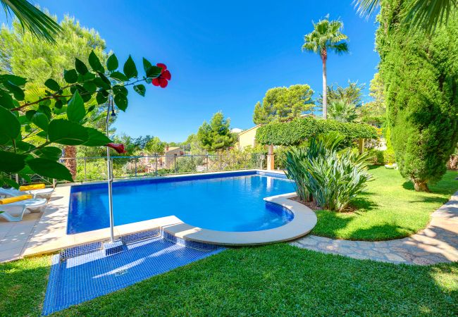 Beautiful garden with green grass around the pool. Pool with grass and a flower garden.